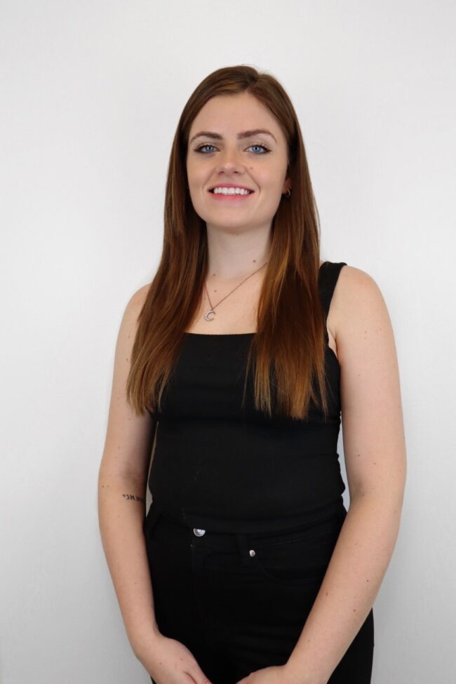 A woman standing wearing a black dress and white background