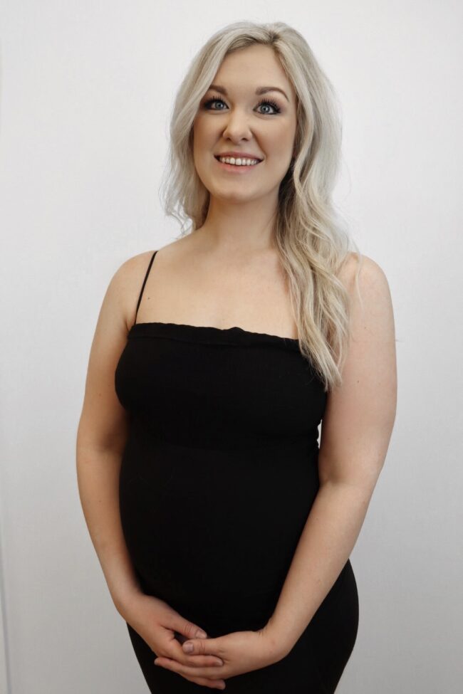 Smiling pregnant woman in black dress.