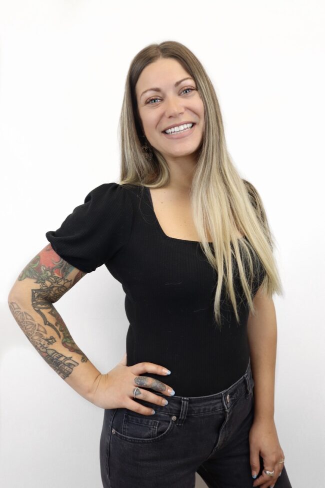 Smiling woman with tattoos and black top.