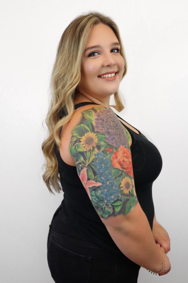 CASSIDY wearing a black dress with a huge flower tattoo on her shoulder