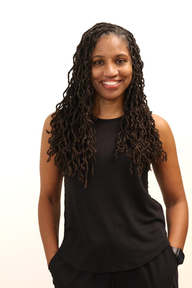 Smiling woman with long brown locs.