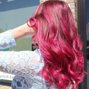 Woman with vibrant pink curly hair.