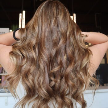 Long brown wavy hair styled back.