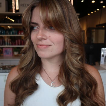 Woman with long brown wavy hair and bangs.